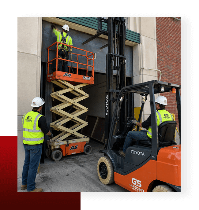 Gooding Solutions technicians installing industrial loading dock door equipment with forklift support.