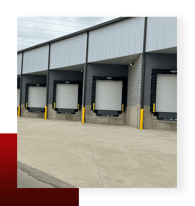 Modern warehouse loading dock doors with dock seals and safety bollards installed by Gooding Solutions.